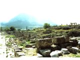 Corinth--Shops along the main city road (Lechaion Road), with Acropolis of Corinth in the background. The Temple of Apollo is on the right